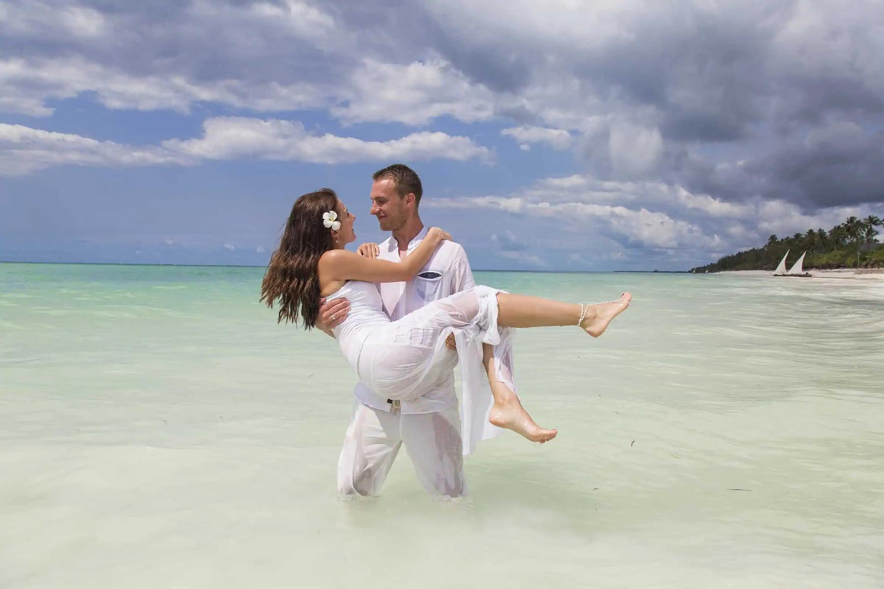 A groom carrying his bride through the turquoise shallows